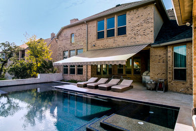 Foto de piscina alargada clásica de tamaño medio a medida en patio trasero con adoquines de hormigón