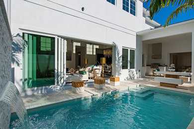 Example of a mid-sized beach style backyard stone and rectangular natural pool fountain design in Miami
