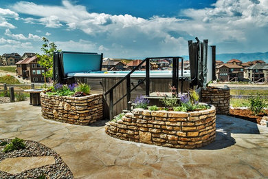 Large backyard stone and rectangular aboveground hot tub photo in Denver