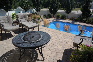 Modelo de piscina alargada clásica grande rectangular en patio trasero con adoquines de hormigón