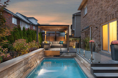 Diseño de piscina con fuente natural minimalista rectangular en patio trasero