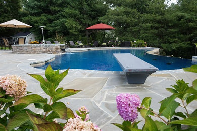 На фото: большой спортивный бассейн произвольной формы на заднем дворе в классическом стиле с джакузи и покрытием из каменной брусчатки с
