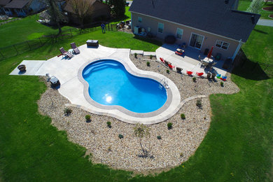 Esempio di una piscina naturale costiera personalizzata di medie dimensioni e dietro casa con lastre di cemento