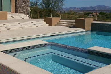 Cette photo montre une piscine à débordement et arrière tendance rectangle avec un bain bouillonnant et des pavés en béton.