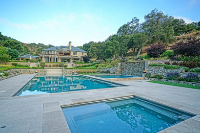 Imagen de piscinas y jacuzzis infinitos contemporáneos grandes rectangulares en patio trasero con adoquines de piedra natural