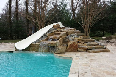 Exempel på en stor klassisk rektangulär pool på baksidan av huset, med vattenrutschkana och marksten i betong
