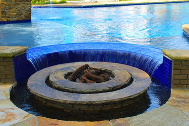 Photo of a medium sized contemporary back custom shaped swimming pool in Birmingham with a water feature and natural stone paving.