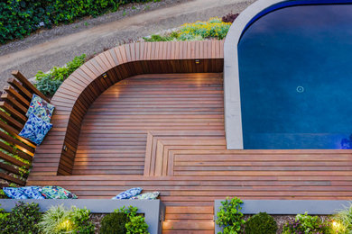Cette image montre un piscine avec aménagement paysager arrière rustique de taille moyenne et sur mesure avec une terrasse en bois.