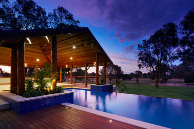 Foto de piscina alargada contemporánea grande rectangular en patio trasero con entablado