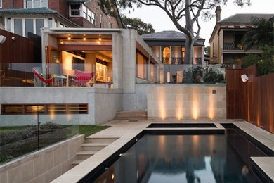 Esempio di una grande piscina a sfioro infinito design rettangolare dietro casa con una vasca idromassaggio e pavimentazioni in pietra naturale