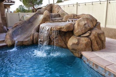 Diseño de piscina con tobogán natural contemporánea de tamaño medio a medida en patio trasero con suelo de hormigón estampado