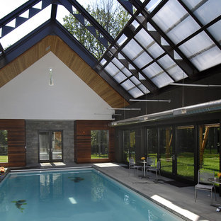 Large contemporary indoor rectangular pool in New York with a pool house and concrete slab.