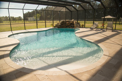Pool - large coastal backyard stone and custom-shaped natural pool idea in Miami