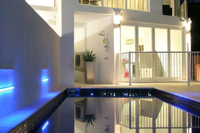 Modelo de piscina alargada minimalista rectangular en patio trasero con suelo de baldosas