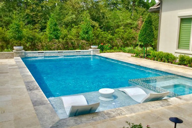 Ejemplo de piscina con fuente alargada tradicional renovada grande rectangular en patio trasero con adoquines de piedra natural