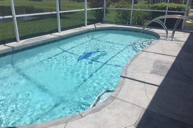 Diseño de piscina alargada contemporánea de tamaño medio tipo riñón en patio trasero con suelo de hormigón estampado