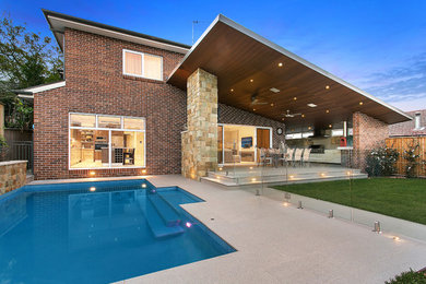 Foto de piscina actual de tamaño medio a medida en patio trasero con adoquines de hormigón