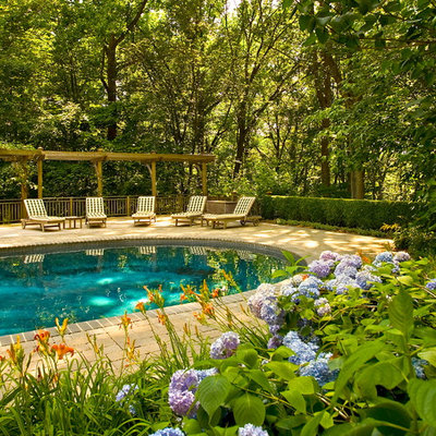 Example of a mid-sized classic brick and round pool design in New York