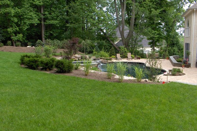 На фото: большой естественный бассейн произвольной формы на переднем дворе в стиле рустика с мощением тротуарной плиткой и джакузи