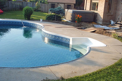 Diseño de piscina marinera grande tipo riñón en patio trasero con losas de hormigón