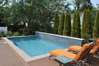 Example of a mid-sized classic backyard rectangular pool fountain design in New York with decking