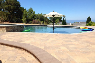 Ejemplo de piscinas y jacuzzis alargados actuales grandes a medida en patio trasero con suelo de baldosas