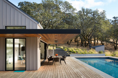 Ejemplo de casa de la piscina y piscina alargada de estilo de casa de campo pequeña rectangular en patio trasero con entablado