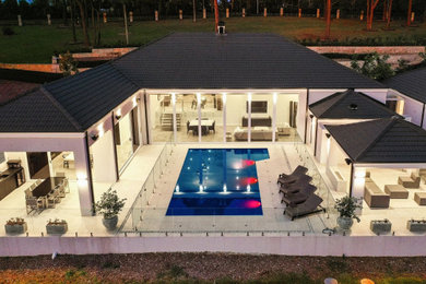 Imagen de piscina alargada extra grande rectangular en patio trasero con paisajismo de piscina y suelo de hormigón estampado