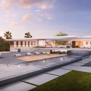 Esempio di un'ampia piscina a sfioro infinito moderna personalizzata dietro casa con fontane e pedane