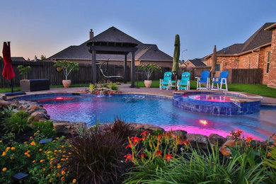 На фото: естественный бассейн среднего размера, произвольной формы на заднем дворе в современном стиле с джакузи и покрытием из бетонных плит