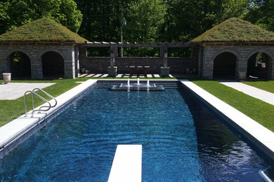 Modelo de piscina con fuente actual grande rectangular en patio trasero con losas de hormigón