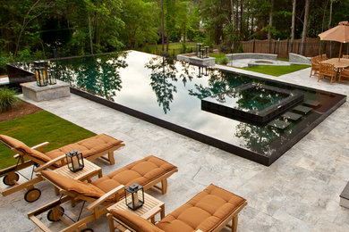 Ejemplo de piscinas y jacuzzis infinitos actuales grandes rectangulares en patio trasero con adoquines de piedra natural