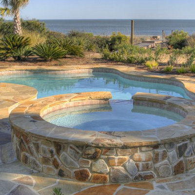 Inspiration for a mid-sized tropical backyard stone and kidney-shaped hot tub remodel in Charleston