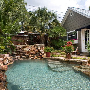 Small country backyard custom-shaped natural pool in Austin with natural stone pavers and a hot tub.