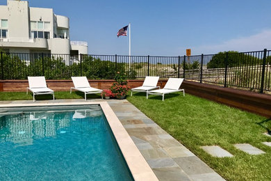 Modelo de piscina alargada marinera de tamaño medio rectangular en patio trasero con adoquines de piedra natural
