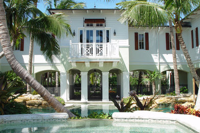 Large island style backyard stone and custom-shaped pool photo in Miami