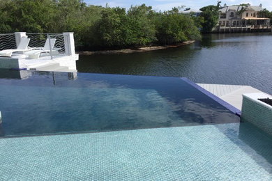 Example of a mid-sized trendy backyard custom-shaped and tile infinity pool fountain design in Miami