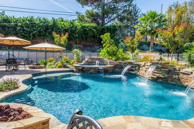 Imagen de piscina con fuente natural clásica renovada de tamaño medio a medida en patio trasero con adoquines de piedra natural