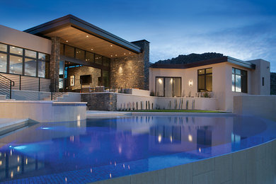 Diseño de piscina infinita actual de tamaño medio a medida en patio trasero con adoquines de piedra natural
