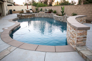 Imagen de piscina clásica de tamaño medio a medida en patio trasero con losas de hormigón