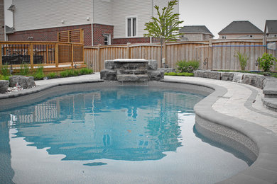 Inspiration for a large timeless backyard concrete paver and custom-shaped pool fountain remodel in Toronto