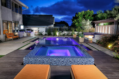 Diseño de piscina con fuente natural actual de tamaño medio rectangular en patio trasero con suelo de baldosas