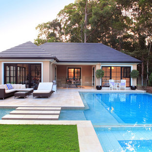 Design ideas for a large transitional backyard custom-shaped pool in Brisbane with a pool house and tile.