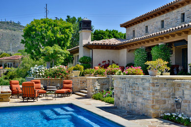 Example of a large tuscan backyard stone and rectangular lap pool design in San Diego