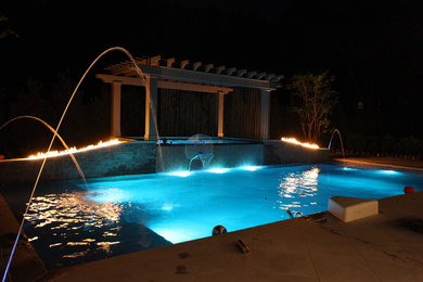Immagine di una grande piscina monocorsia chic rettangolare dietro casa con una vasca idromassaggio e piastrelle