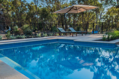 Ejemplo de piscina infinita campestre de tamaño medio rectangular en patio trasero con adoquines de hormigón