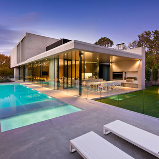 Photo of a large modern backyard rectangular lap pool in Melbourne with concrete slab and a hot tub.