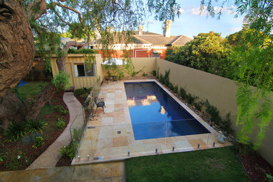 Diseño de piscina tradicional de tamaño medio rectangular en patio trasero con adoquines de piedra natural