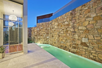 Diseño de piscina alargada contemporánea pequeña a medida en patio lateral con adoquines de piedra natural