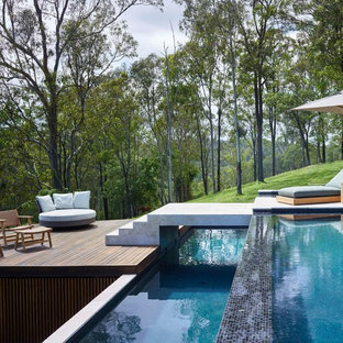 Ispirazione per una piscina a sfioro infinito moderna rettangolare dietro casa con pedane